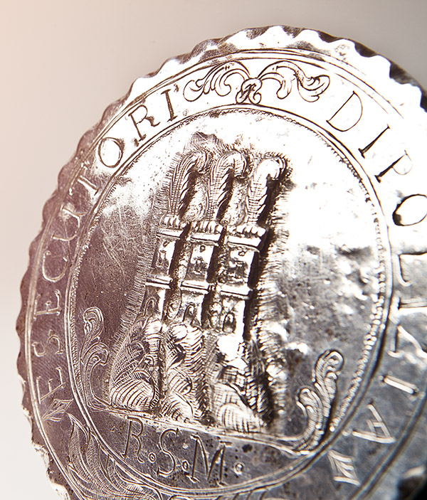 Close up di una moneta storica della Repubblica di San Marino. Sopra c'è raffigurate le tre torri di San Marino e attorno una scritta che ne determina la provenienza. a differenza delle monete più comuni, sul bordo c'è una smussatura decorativa ad onde.